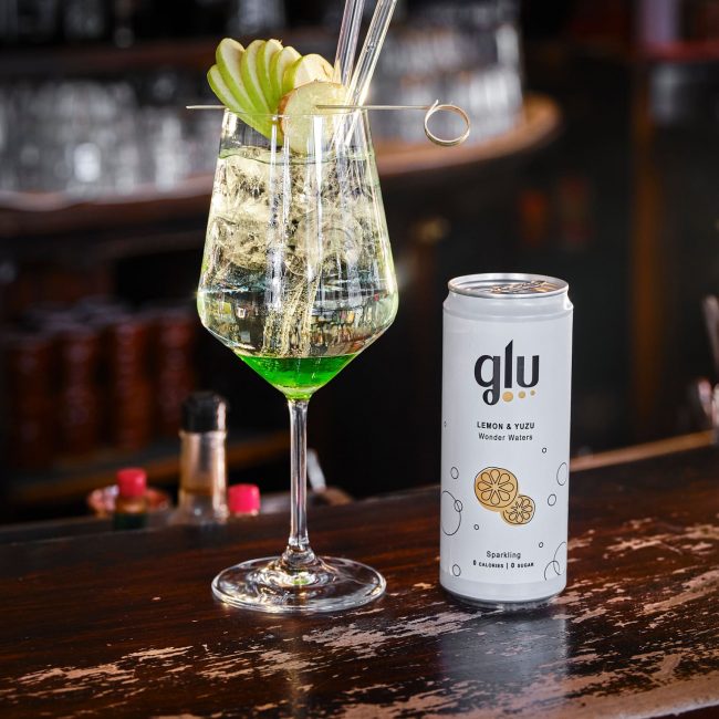 Lattina di Glu Lemon & Yuzu accanto ad un cocktail prodotto usando Glu sparkling waters