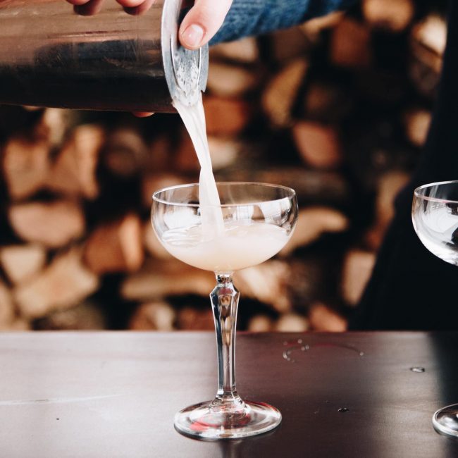 Cocktail di color panna mentre viene versato in un bicchiere a coppa