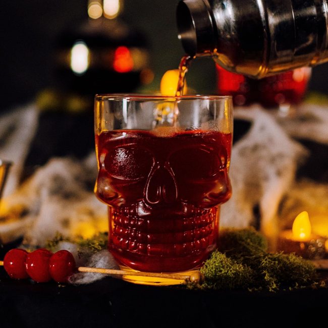 Cocktail di colore rosso in un bicchiere a forma di teschio stile ballon